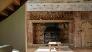 Una habitación acogedora con chimenea de ladrillo, un banco de madera y techo rústico.