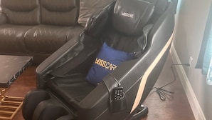 A massage chair with a 'Bosscar' logo, a blue pillow with 'Bosscar' text, and a wooden floor. - Luxury Downtown Condo (Clearfield)