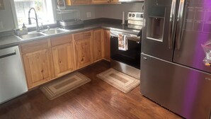 A kitchen with wooden cabinets, stainless steel appliances, a microwave, oven, and refrigerator. - Luxury Downtown Condo (Clearfield)