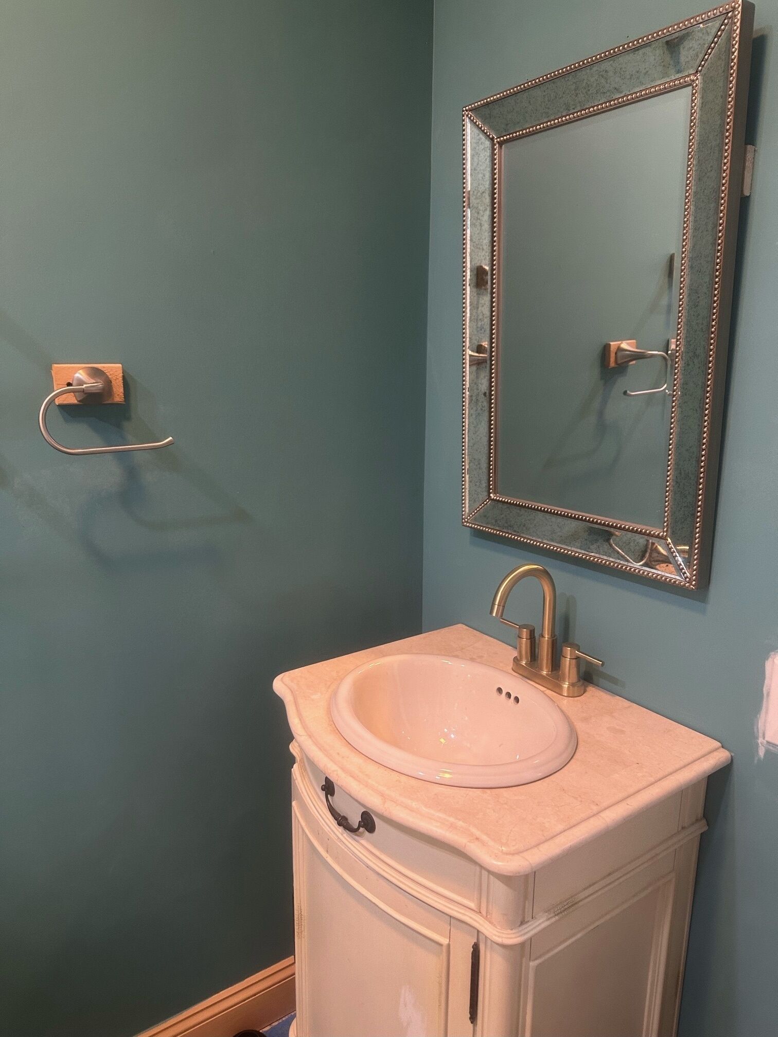 A bathroom with a sink, mirror, and towel rack.