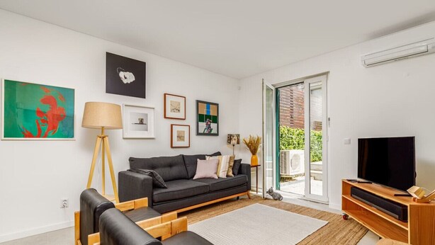 A modern living room with a grey sofa, wooden coffee table, and a flat-screen TV. - Haus Abel - with pool and garden in central Lisbon (Lisboa)