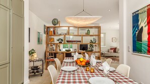 A dining area with a checkered tablecloth, a fruit bowl, and a bookshelf. - Haus Abel - with pool and garden in central Lisbon (Lisboa)