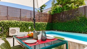 An outdoor dining area with a pool, green chairs, and a table set for two. - Haus Abel - with pool and garden in central Lisbon (Lisboa)