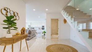 A modern living room with a glass staircase, a dining area, and a kitchen in the background. - Axess Villa with panoramic ocean view (Lisboa)