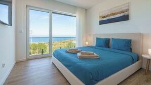 A bedroom with a large bed, a view of the sea, and a painting on the wall. - Axess Villa with panoramic ocean view (Lisboa)