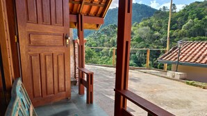 A wooden door leading to a balcony with a view of a mountainous landscape. - Pousada Olivier da Montanha (Santo Antonio do Pinhal)
