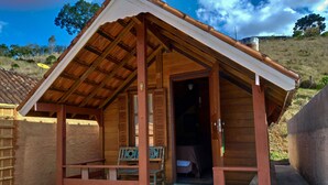 A wooden cabin with a sloped roof, a bench outside, and a door leading inside. - Pousada Olivier da Montanha (Santo Antonio do Pinhal)