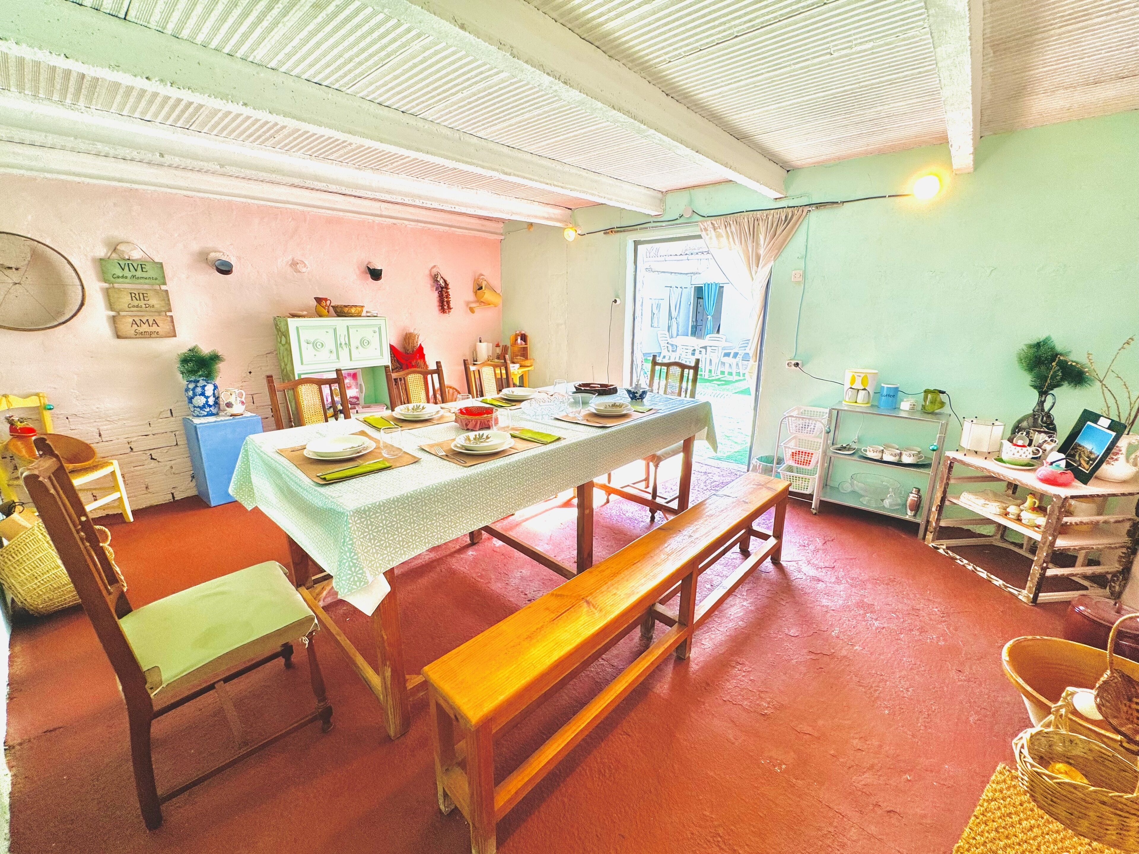 Un comedor con una larga mesa dispuesta para una comida, rodeada de sillas.
