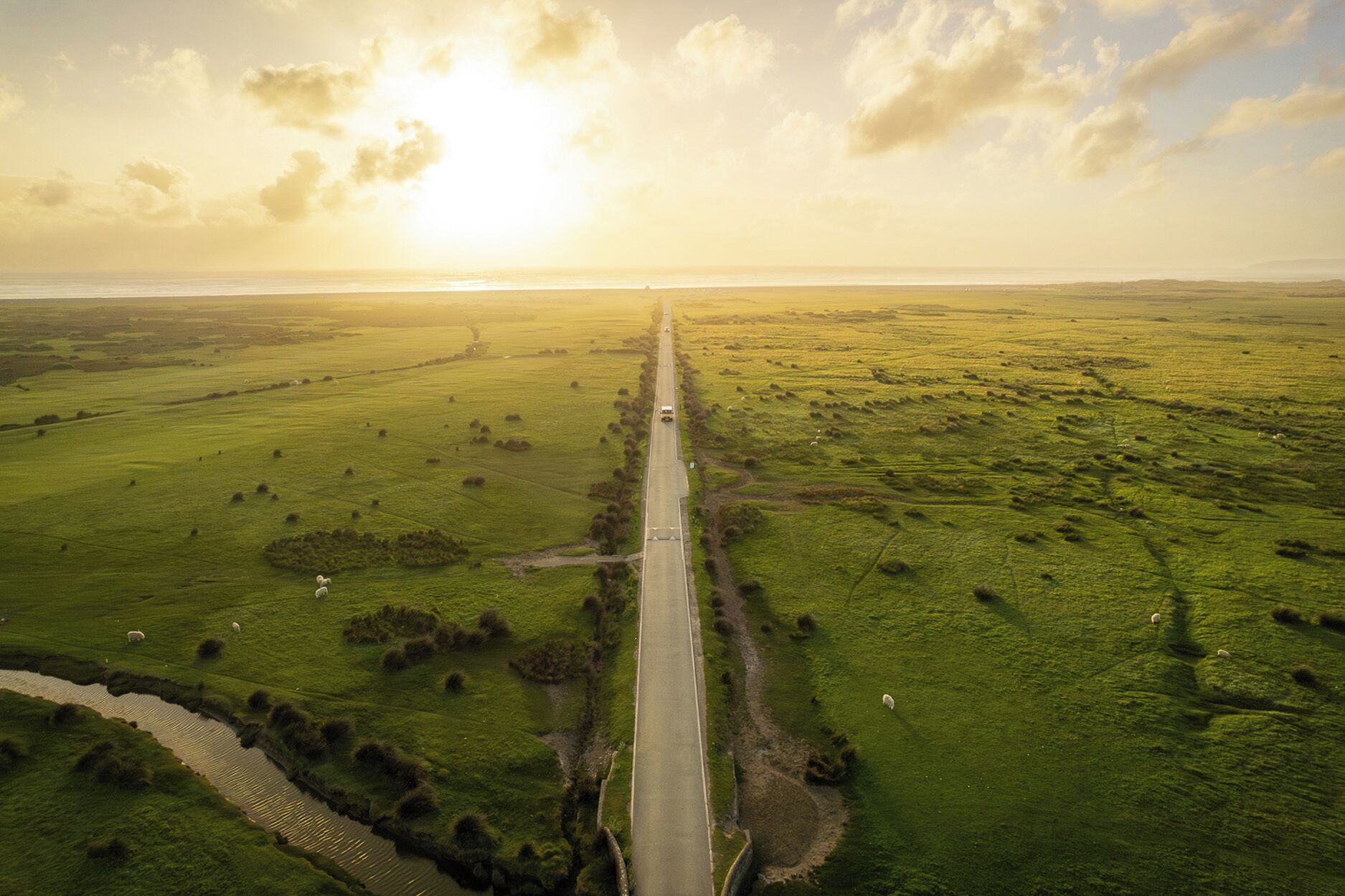 Une route droite traversant un paysage verdoyant, sous un ciel dégagé.