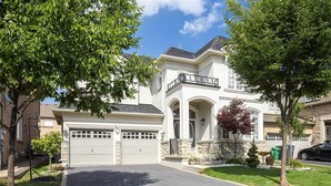 A two-story house with a garage, a driveway, and a well-maintained lawn. - Spacious Family Haven: Modern 4-bedroom Luxury Home (Brampton)