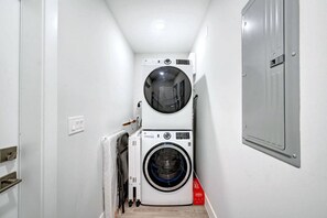 Un cuarto de lavandería con dos lavadoras apiladas y una secadora.