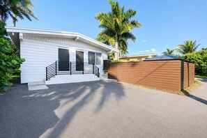 A modern single-story house with a white exterior, a front porch with black railings, and a brown fence. - Walk to Beach Luxury 4BR/4BA Villa Hollywood Lakes (Hollywood)
