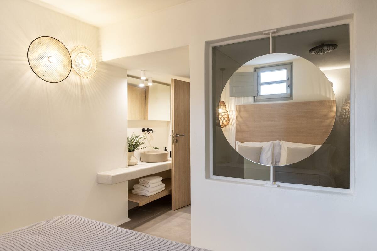 Un baño moderno con un espejo redondo, un lavabo y un perchero para toallas.