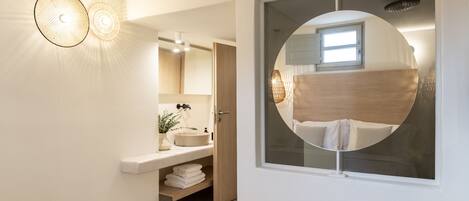 A modern bathroom with a round mirror, a sink, and a towel rack.