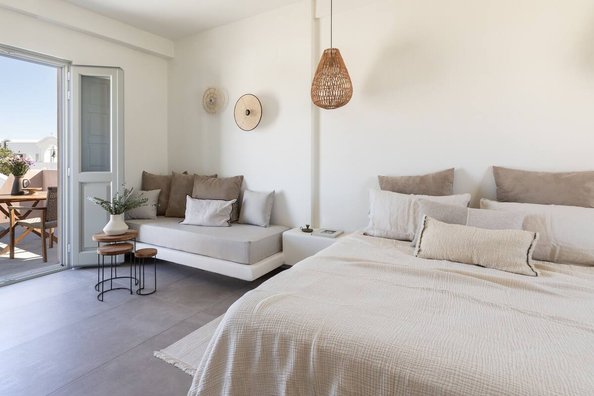 Un dormitorio moderno con sofá cama, una cama grande y una zona de comedor con mesa y sillas.