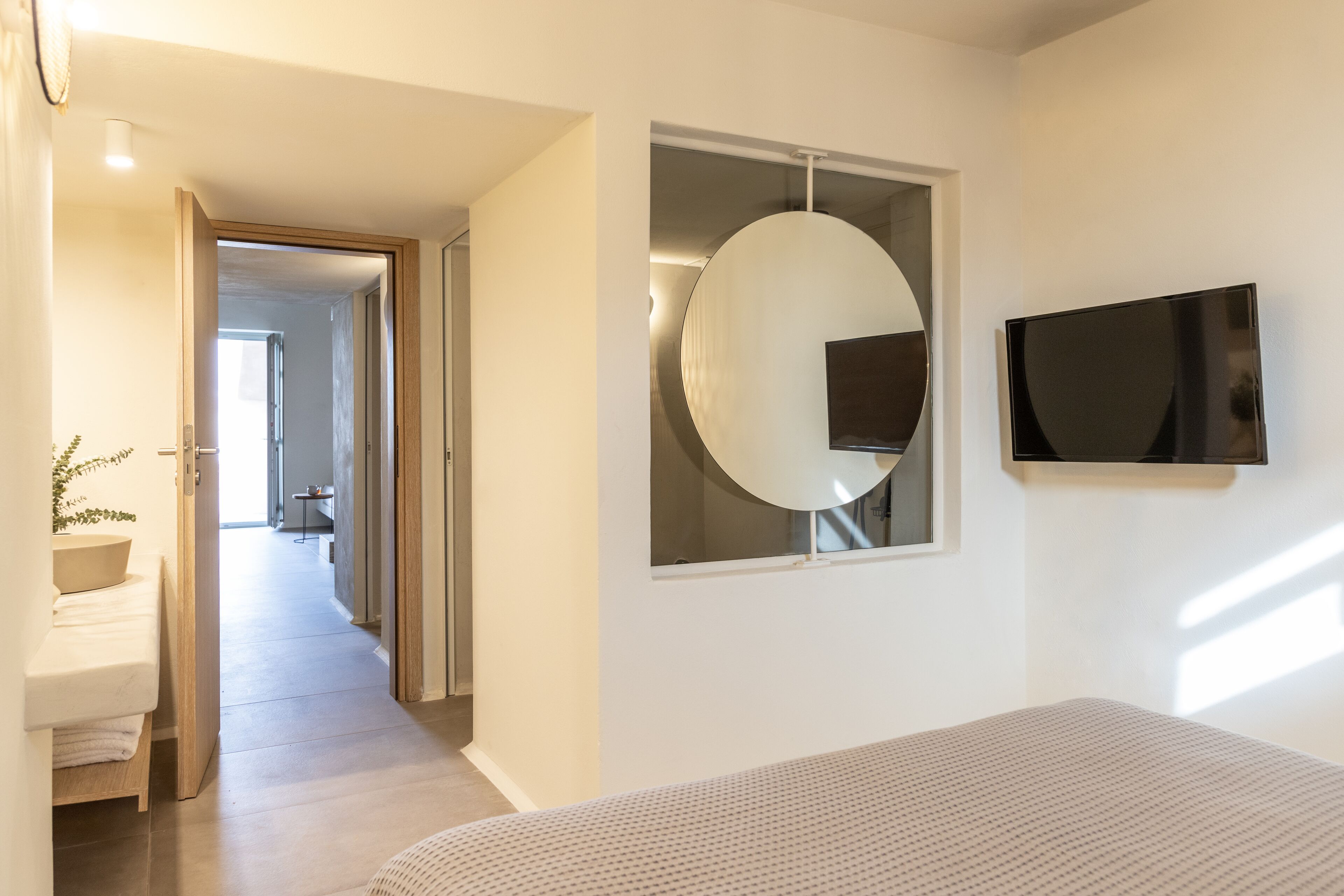 A modern bedroom with a bed, a TV, and a large mirror.