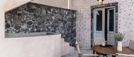 A stone wall, a wooden table with chairs, and a door with a light fixture.