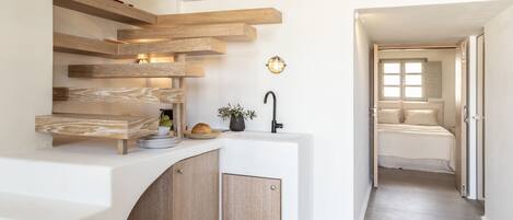 Una cocina moderna con estantes de madera, un lavamanos y una pequeña planta.
