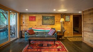 A cozy room with a wooden interior, a leather sofa, a patterned rug, and a painting on the wall.