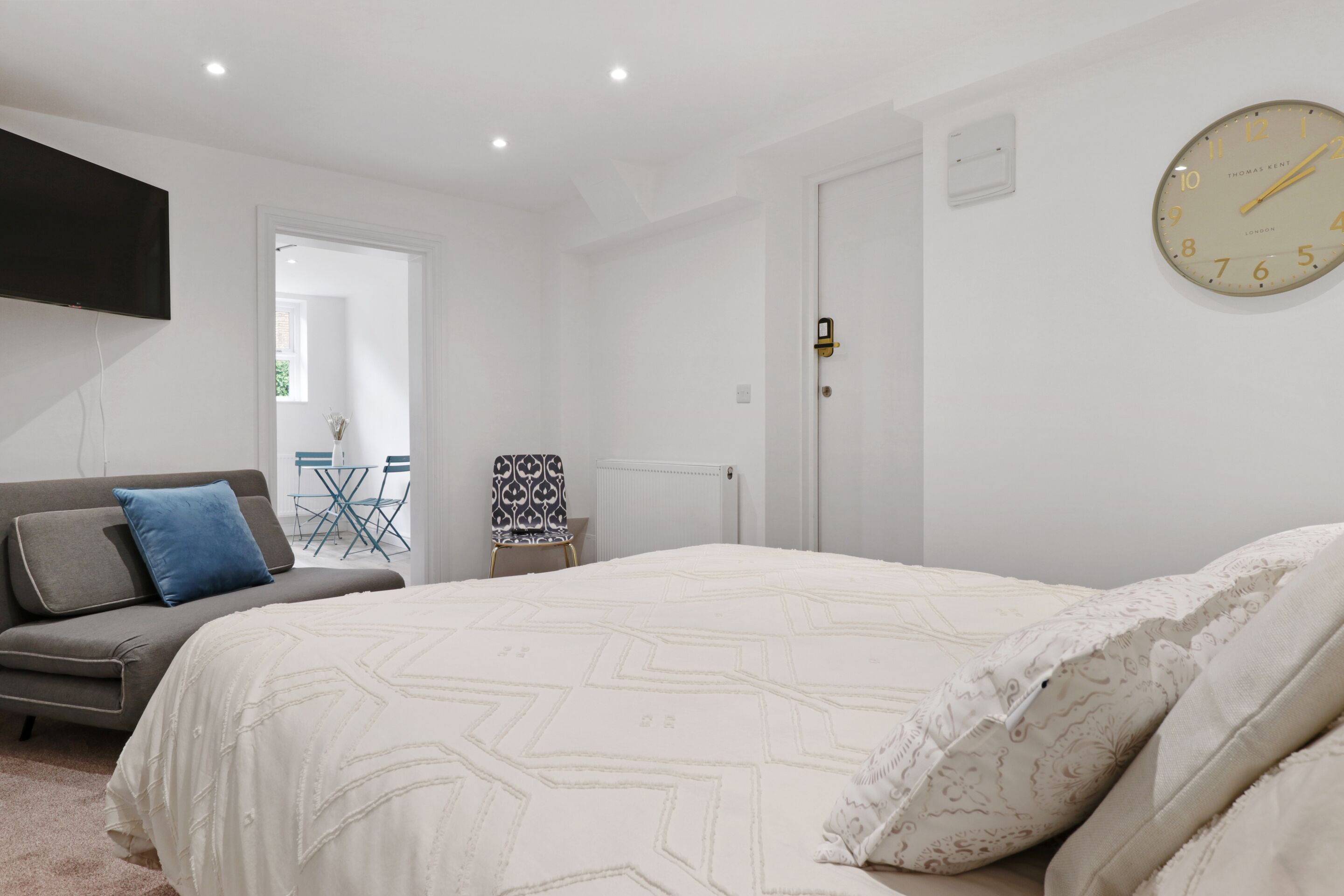 Ein Schlafzimmer mit einem großen Bett, einem Sofa, einem Fernseher und einer Wanduhr.
