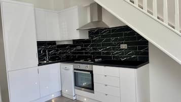 A modern kitchen with white cabinetry, black marble backsplash, and a built-in oven.
