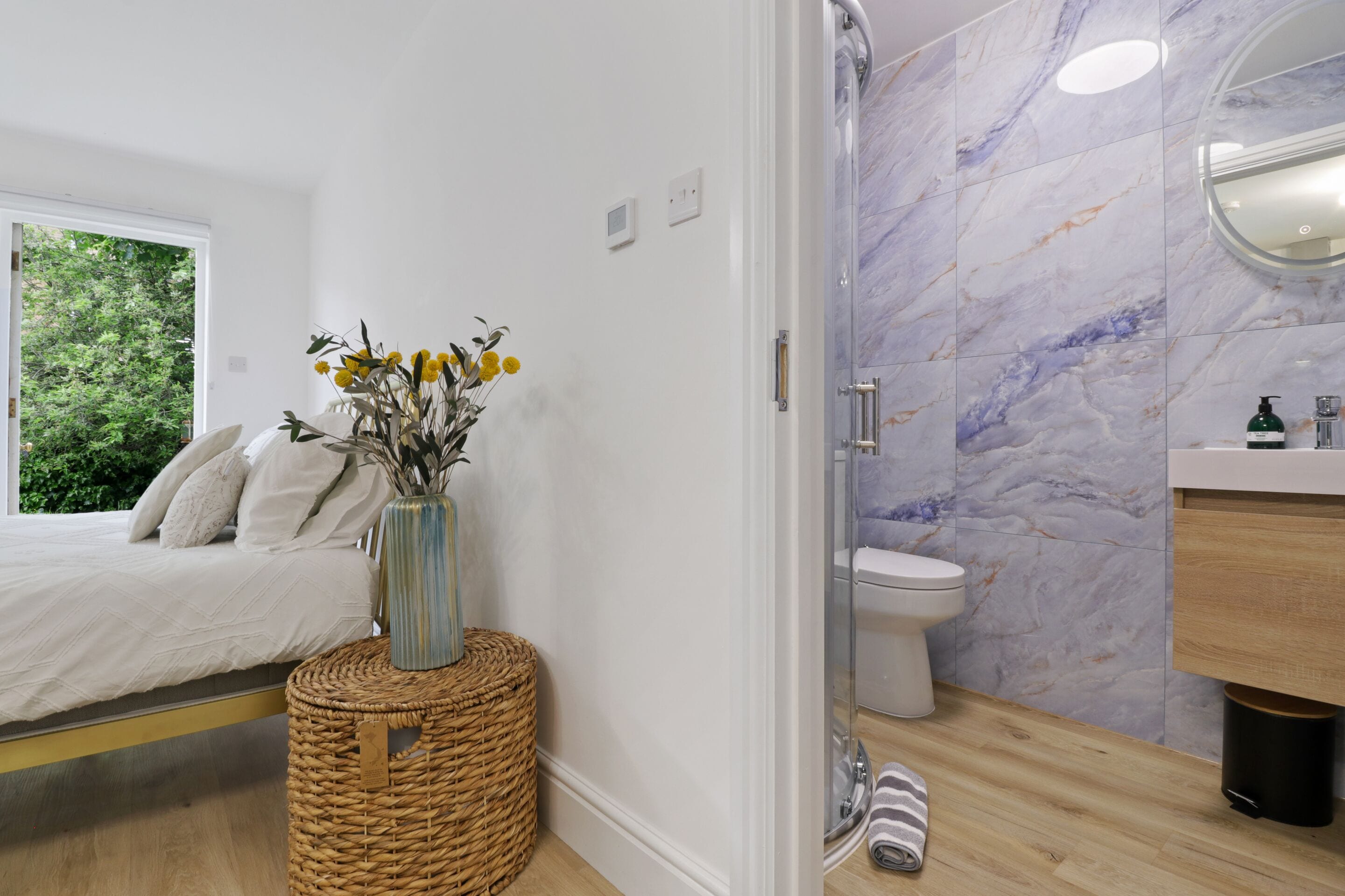 Een moderne badkamer met een douchewand van marmer, een toilet en een houten wastafelmeubel.