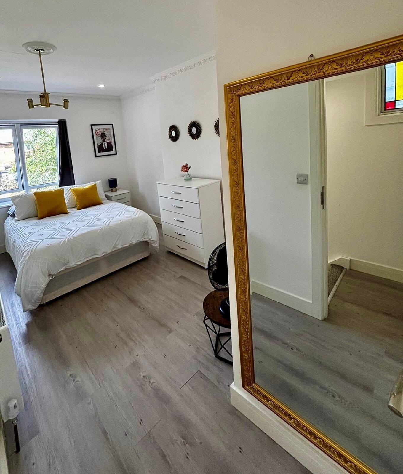 A bedroom with a bed, a dresser, a mirror, and a ceiling fan.