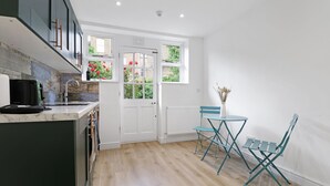 Cocina moderna con encimera de mármol, cafetera negra y ventana con vistas a flores rojas.