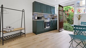 Una cocina moderna con armarios verde oscuro, horno empotrado y ventana con vistas a un jardín.