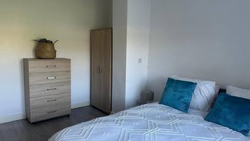 A bedroom with a bed, a wardrobe, and a bedside table.