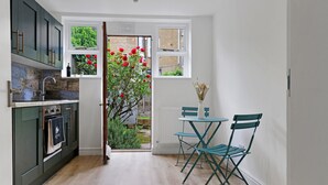 Una cocina moderna con armarios oscuros, horno empotrado y ventana con vistas a un jardín con flores rojas.