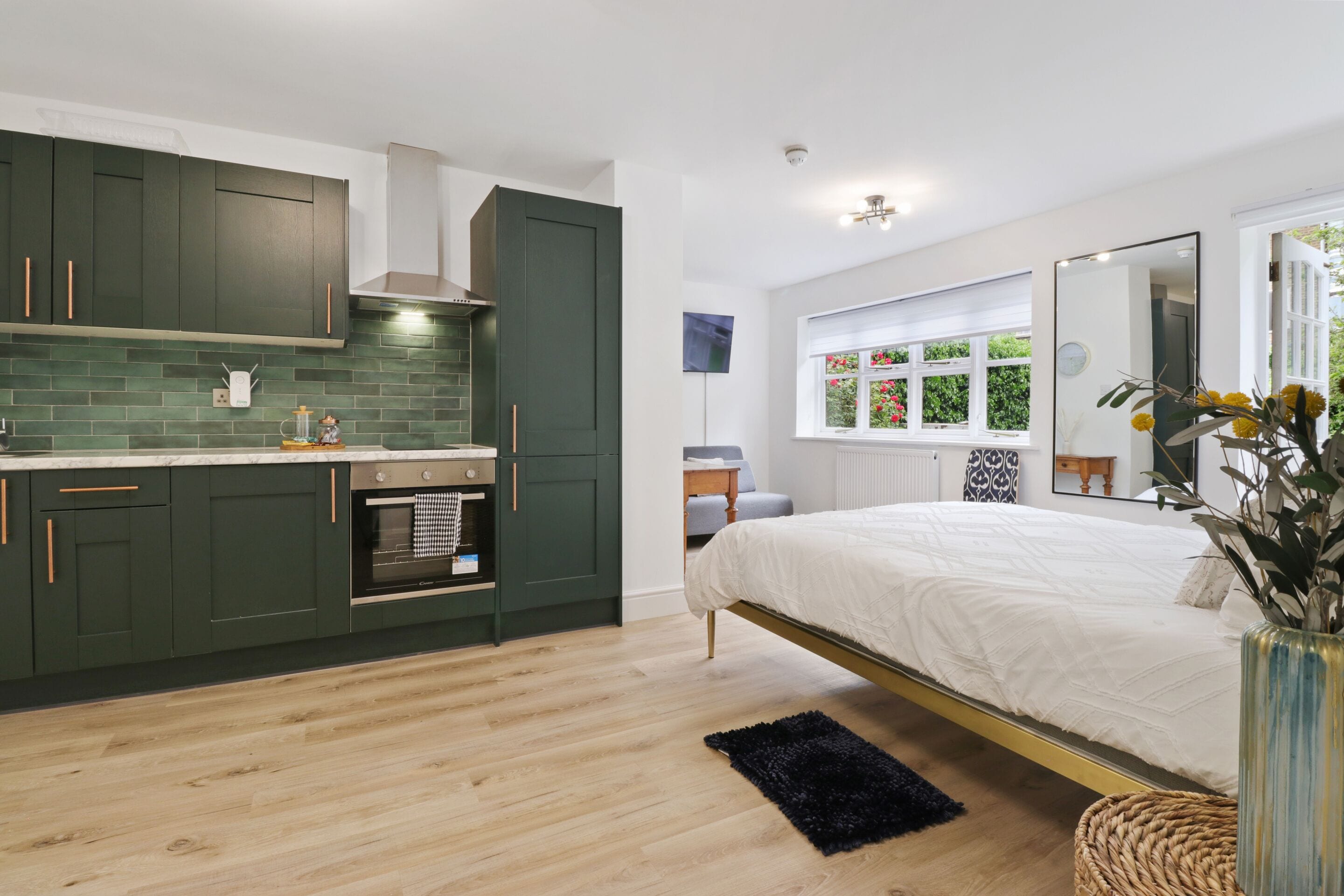 A modern kitchen with dark green cabinets, a white countertop, and a built-in oven.