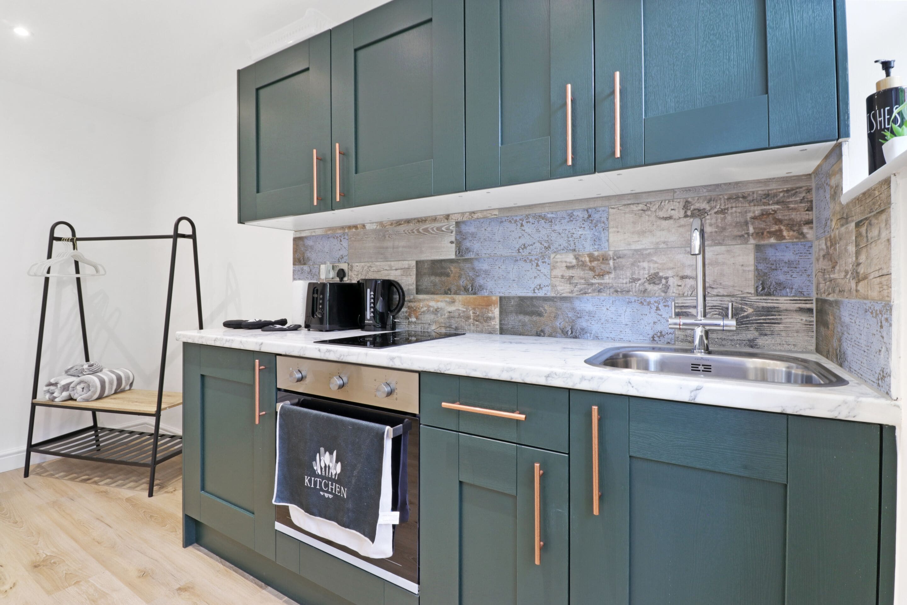 Una cocina moderna con armarios color turquesa, encimera de mármol y horno empotrado.