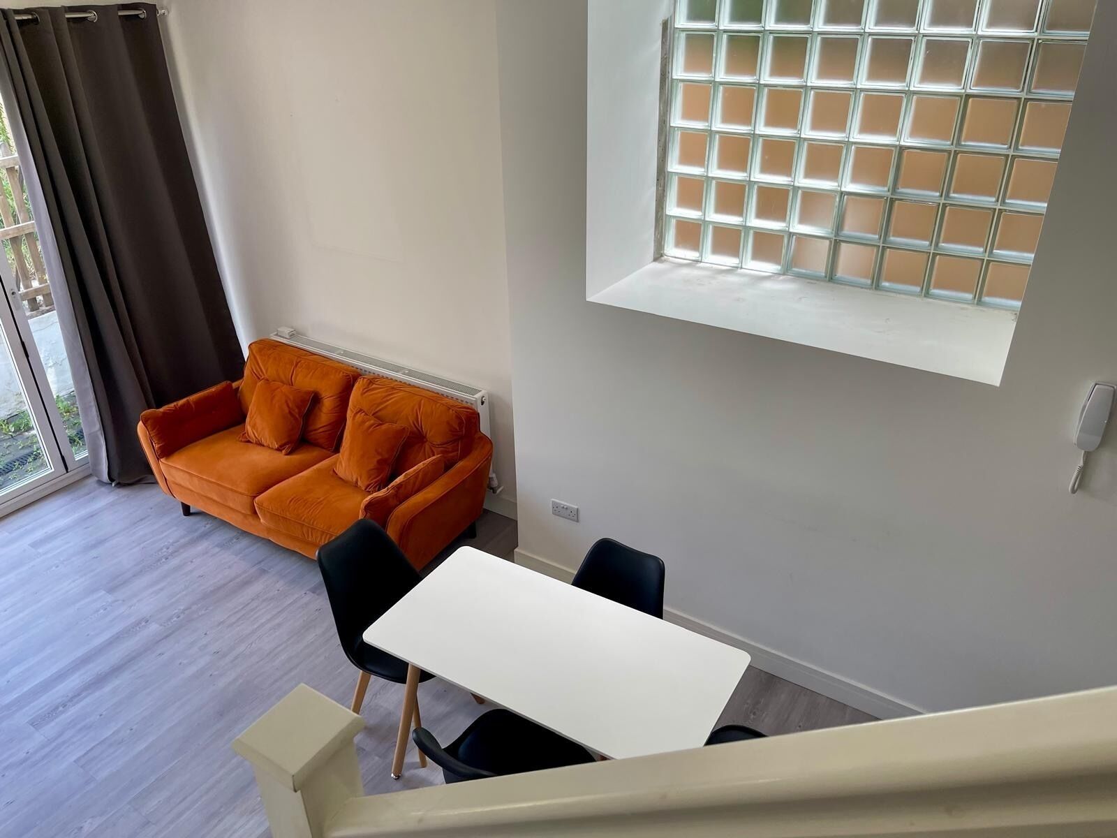 Un salón moderno con un sofá, una mesa de comedor y una ventana con diseño de cuadrícula.