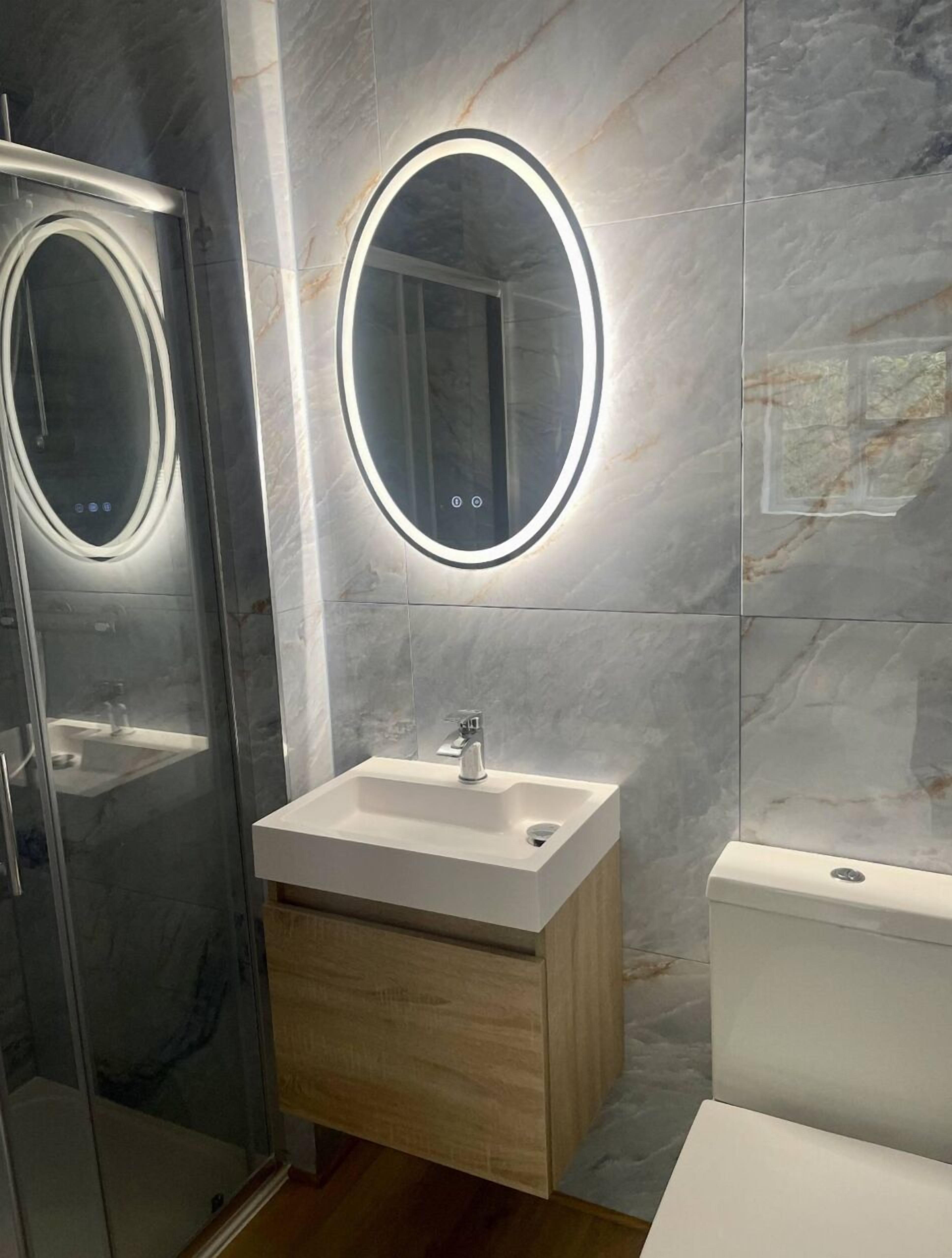 A modern bathroom with a glass shower enclosure, a wooden vanity with a white sink, and a toilet.