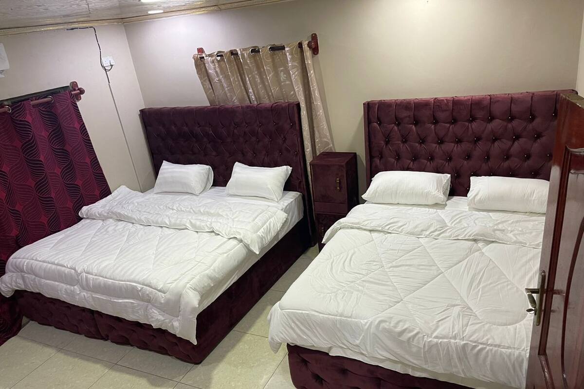 Ein Hotelzimmer mit zwei Betten, jeweils mit einem gesteppten Kopfteil und weißer Bettwäsche.