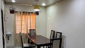 A dining area with a rectangular table, six chairs, a pendant light, and a curtain. - ELITE HOME STAYS (Lusaka)