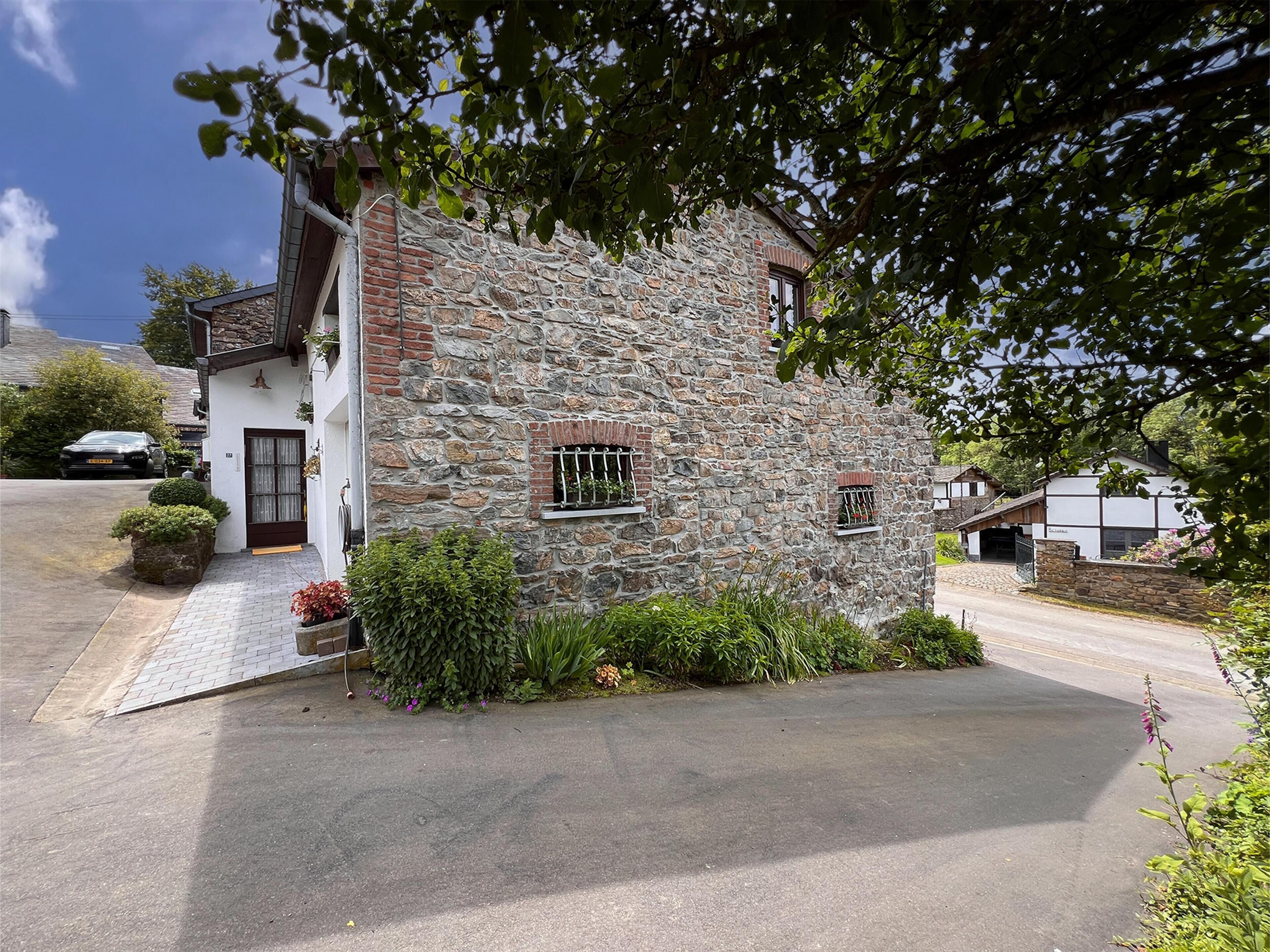 Una casa in pietra con facciata bianca, una porta d'ingresso e una piccola finestra con sbarre.