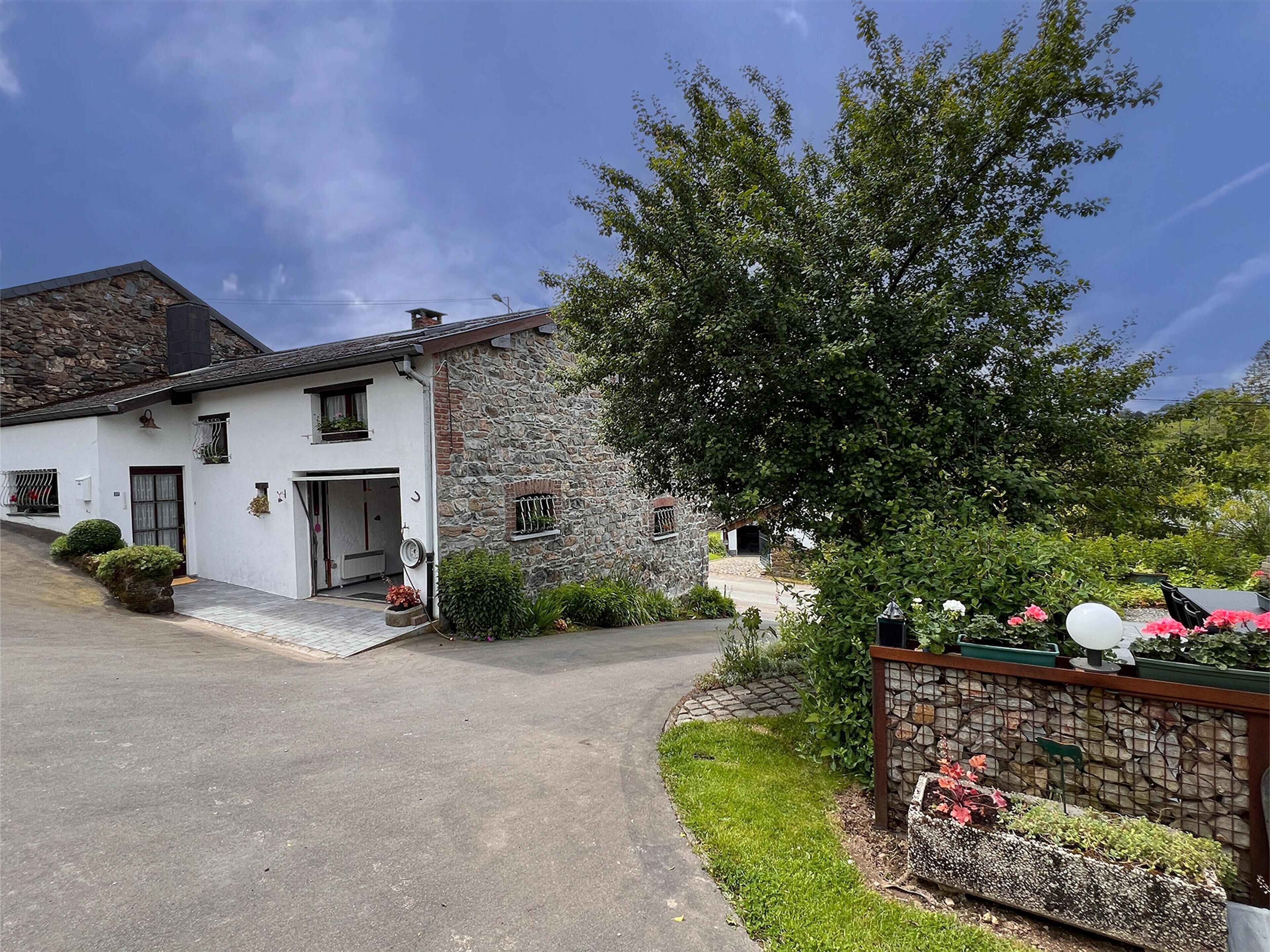 Uma casa de dois andares com fachada de pedra e exterior branco.