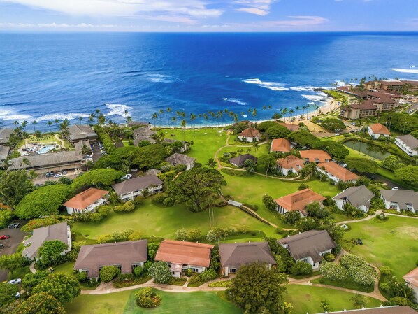 An aerial view of a coastal residential area with houses, a golf course, and a beach. - Remodeled #56, AC, grnd flr end unit, ideal location! (Koloa)
