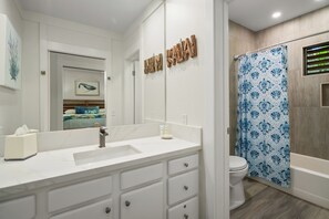 Une salle de bain moderne avec un meuble-lavabo blanc, un grand miroir et un rideau de douche à motifs bleus.
