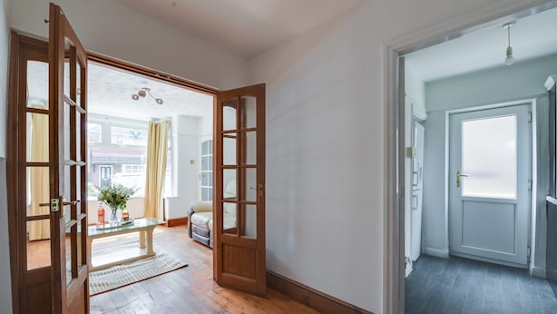 A hallway with wooden flooring, a glass table with a vase, and a sofa. - Remarkable 3-bed House in Middleton Manchester (Manchester)