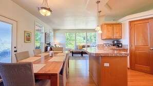A spacious kitchen with wooden cabinets, a large island, and a dining area with wicker chairs and a table.