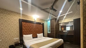 A well-lit bedroom with a large bed, a ceiling fan, and a mirror. - Hotel Classio Kormangala (Bengaluru)