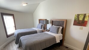 A bedroom with two beds, a window, and a ceiling light.