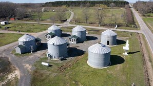 A rural landscape with several large cylindrical silos and smaller buildings, likely used for storage or grain.