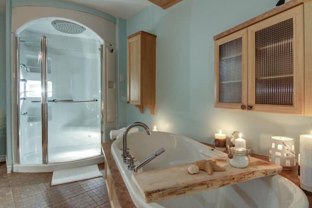 Une salle de bain dotée d’une douche à parois de verre, d’une baignoire sur pieds, de meubles en bois et d’un sol carrelé.