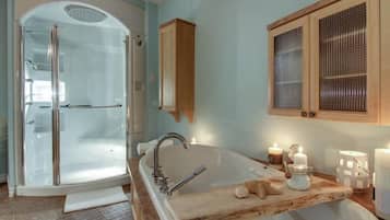 Une salle de bain dotée d’une douche à parois de verre, d’une baignoire sur pieds, de meubles en bois et d’un sol carrelé.