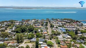 Vue aérienne d’un quartier résidentiel situé sur la côte, avec des maisons, des routes et un port de plaisance.