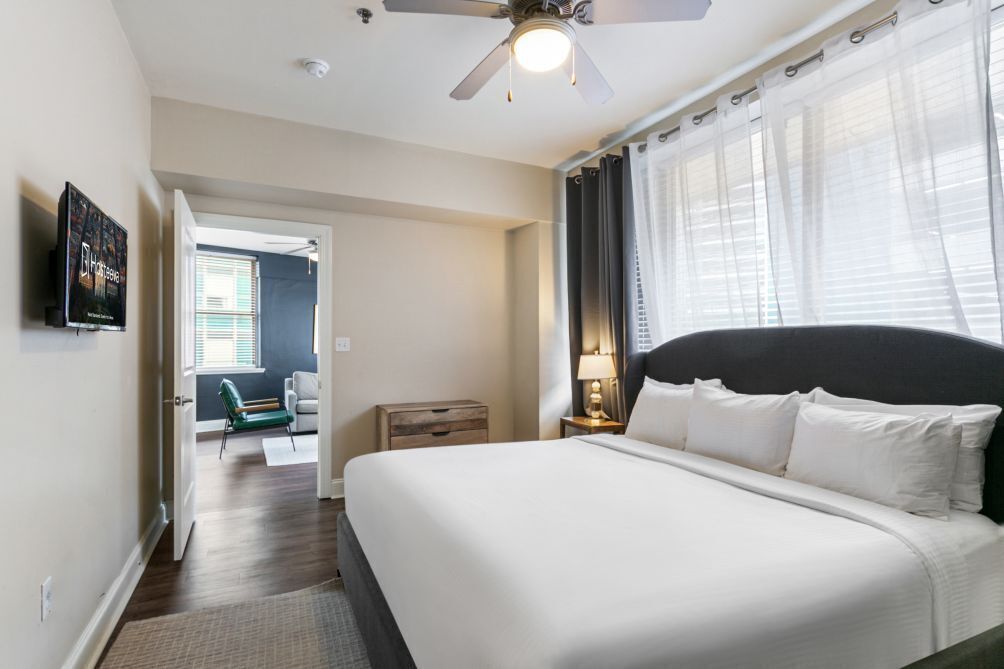 Ein Hotelzimmer mit einem großen Bett, einem Deckenventilator, einem an der Wand montierten Fernseher und Blick ins Freie.